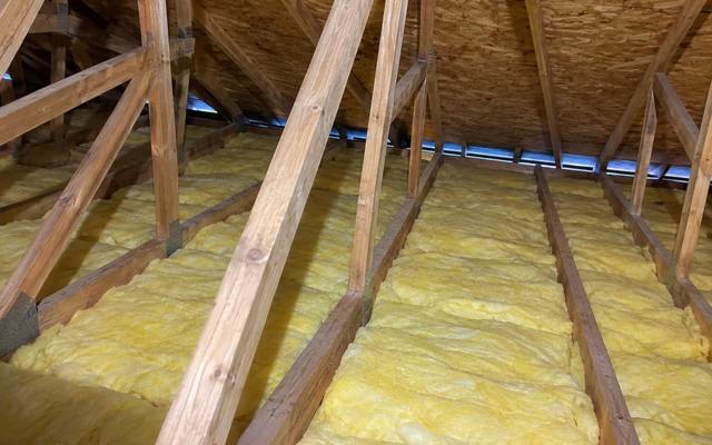 Yellow batt insulation between attic joists, with vent baffles along the eaves
