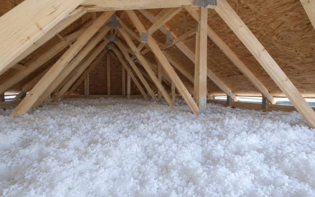 Deep white blown-in fiberglass under the truss webs, with soffit vents along the eaves